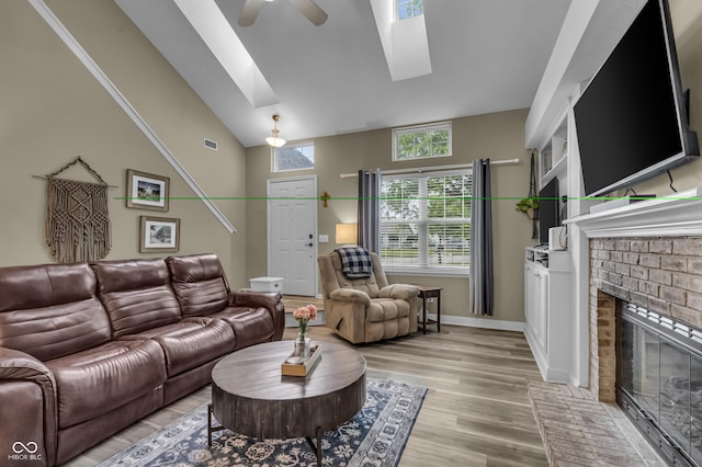 10832 Washington Bay Dr, Fishers, IN 46037 - living area with a skylight, a ceiling fan, light wood-type flooring, a brick fireplace, and vaulted ceiling