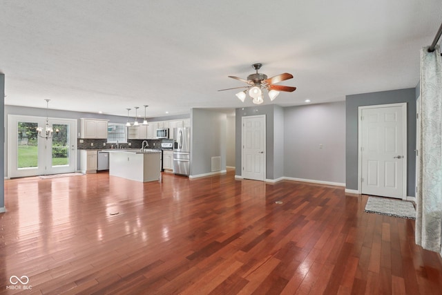 151 S St, Southport, IN 46227 - unfurnished living room with dark wood-type flooring, a ceiling fan, and a chandelier