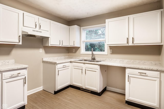 3613 Moller Rd, Indianapolis, IN 46224 - kitchen featuring under cabinet range hood, white cabinets, light wood finished floors, and a textured ceiling