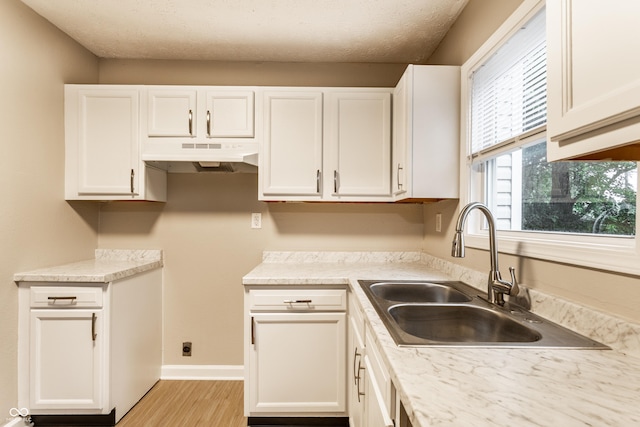 3613 Moller Rd, Indianapolis, IN 46224 - kitchen with under cabinet range hood, white cabinetry, light wood-style flooring, light countertops, and a textured ceiling