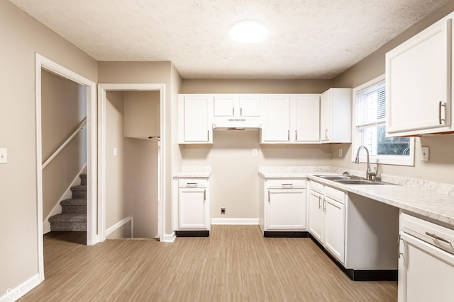 3613 Moller Rd, Indianapolis, IN 46224 - kitchen with under cabinet range hood, light wood-type flooring, white cabinets, and a textured ceiling