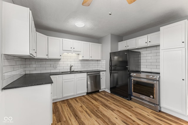 748 Maple Ln, Brownsburg, IN 46112 - kitchen with stainless steel dishwasher, freestanding refrigerator, dark countertops, light wood-style flooring, and white cabinets