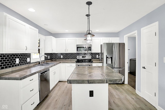 6059 Buck Blvd, Indianapolis, IN 46237 - kitchen featuring appliances with stainless steel finishes, tile counters, a kitchen island, tasteful backsplash, and white cabinets