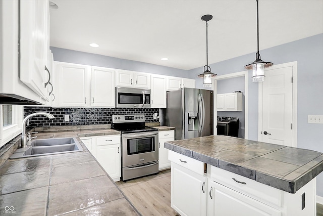 6059 Buck Blvd, Indianapolis, IN 46237 - kitchen featuring appliances with stainless steel finishes, independent washer and dryer, light wood-type flooring, tasteful backsplash, and decorative light fixtures