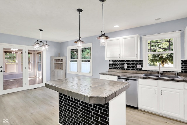 6059 Buck Blvd, Indianapolis, IN 46237 - kitchen featuring stainless steel dishwasher, light wood finished floors, tile counters, white cabinetry, and tasteful backsplash