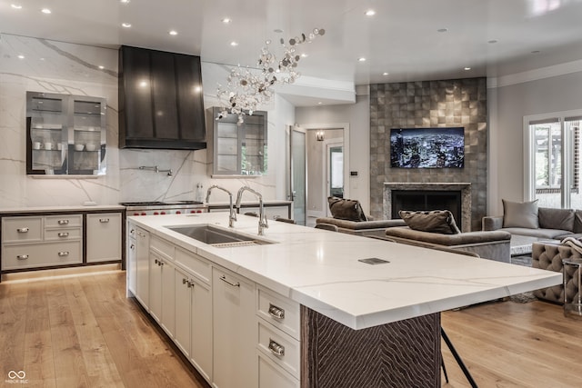520 Willow Spring Rd, Indianapolis, IN 46240 - kitchen featuring open floor plan, light wood finished floors, light stone counters, a center island with sink, and wall chimney range hood