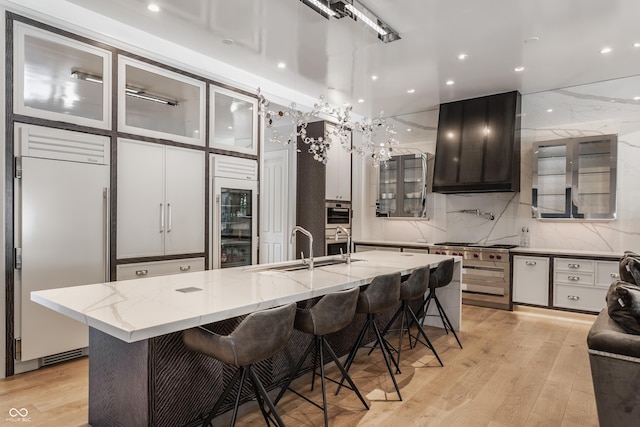 520 Willow Spring Rd, Indianapolis, IN 46240 - kitchen featuring high quality appliances, ventilation hood, beverage cooler, light wood-style floors, and glass insert cabinets