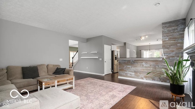 12817 Mojave Dr, Fishers, IN 46037 - living area featuring dark wood-style floors, stairs, plenty of natural light, track lighting, and a textured ceiling