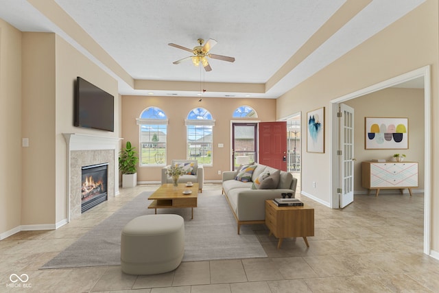 2815 Grandview Ln, Greenwood, IN 46143 - living area featuring a ceiling fan, a tiled fireplace, a tray ceiling, and light tile patterned floors