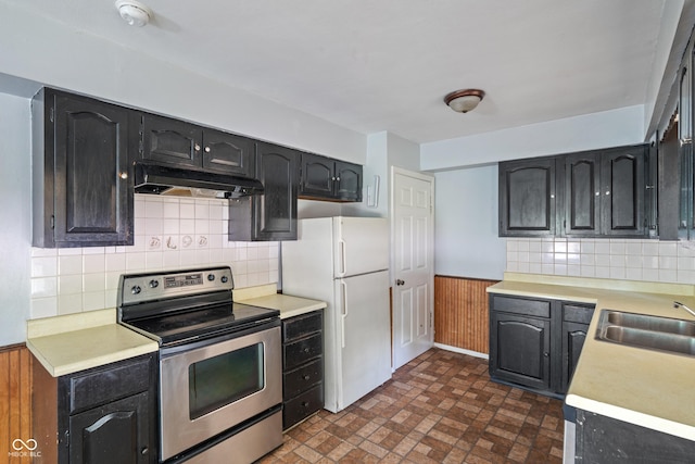 3408 Harvest Ave, Indianapolis, IN 46226 - kitchen featuring stainless steel electric range oven, under cabinet range hood, freestanding refrigerator, a wainscoted wall, and light countertops