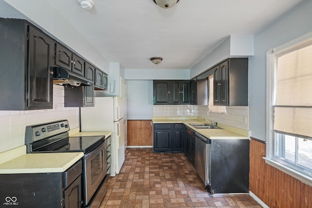 3408 Harvest Ave, Indianapolis, IN 46226 - kitchen with stainless steel appliances, under cabinet range hood, a wainscoted wall, brick patterned flooring, and light countertops