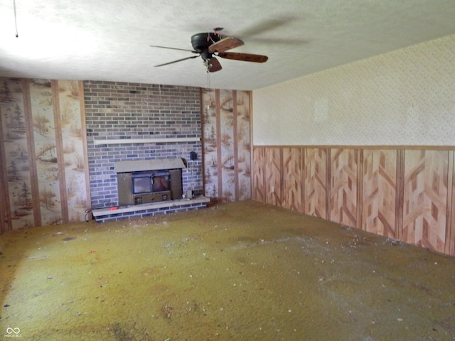 3926 S County Road 550 W, Coatesville, IN 46121 - unfurnished living room with wallpapered walls, ceiling fan, a fireplace, and a wainscoted wall
