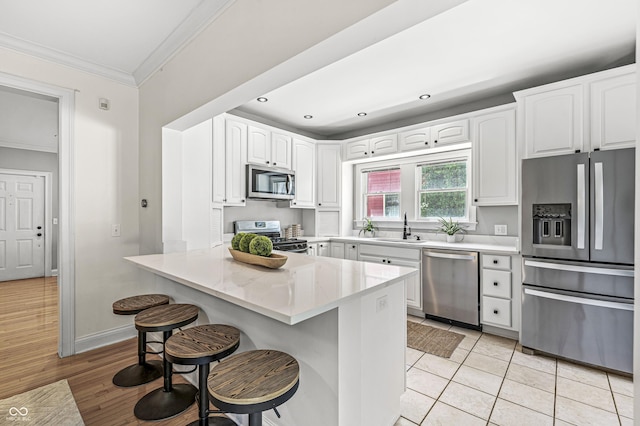 4920 Central Ave, Indianapolis, IN 46205 - kitchen featuring appliances with stainless steel finishes, crown molding, a breakfast bar, a peninsula, and white cabinets