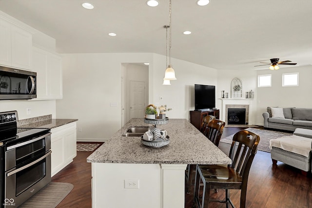 13525 Forest Glade Dr, Fishers, IN 46037 - kitchen with stainless steel appliances, a ceiling fan, recessed lighting, light stone counters, and a breakfast bar area