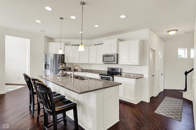 13525 Forest Glade Dr, Fishers, IN 46037 - kitchen featuring appliances with stainless steel finishes, recessed lighting, dark wood-style flooring, an island with sink, and a kitchen breakfast bar