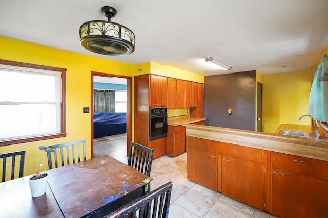 4 Kentwood Dr, Greencastle, IN 46135 - kitchen featuring black oven, healthy amount of natural light, light tile patterned flooring, and a peninsula