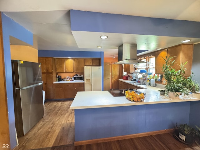 8394 E Mulberry St, Columbus, IN 47203 - kitchen with appliances with stainless steel finishes, island range hood, brown cabinetry, a peninsula, and light wood finished floors