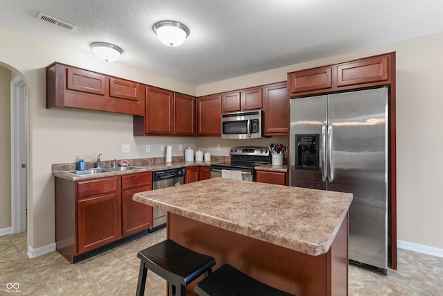 546 Greenwood Trace Dr, Whiteland, IN 46184 - kitchen with stainless steel appliances, arched walkways, a kitchen island, a kitchen breakfast bar, and a textured ceiling
