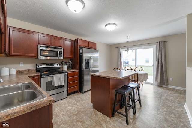 546 Greenwood Trace Dr, Whiteland, IN 46184 - kitchen with appliances with stainless steel finishes, a kitchen breakfast bar, a center island, pendant lighting, and a textured ceiling