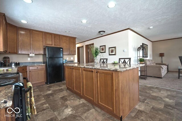 160 Lazy River Pl, Cloverdale, IN 46120 - kitchen featuring freestanding refrigerator, stove, a center island with sink, light stone counters, and brown cabinets