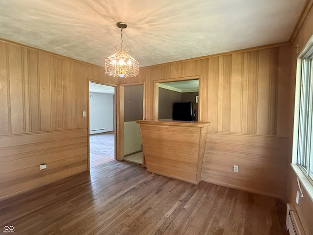 2212 Hanover Dr, Indianapolis, IN 46227 - unfurnished dining area featuring a chandelier, a baseboard radiator, baseboard heating, wood walls, and hardwood / wood-style flooring