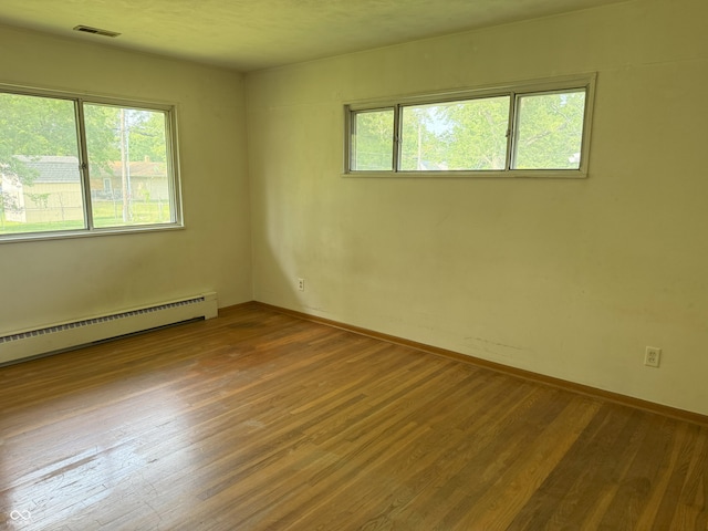 2212 Hanover Dr, Indianapolis, IN 46227 - empty room featuring plenty of natural light, wood finished floors, and a baseboard heating unit