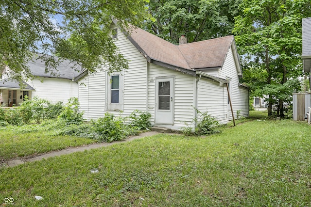 3445 Graceland Ave, Indianapolis, IN 46208 - view of side of home with roof with shingles, a yard, and a chimney