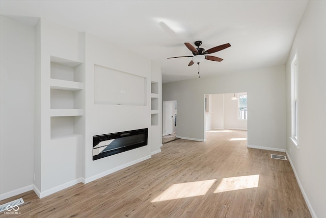 312 E Columbia St, Attica, IN 47918 - unfurnished living room with light wood-style floors, a glass covered fireplace, a ceiling fan, and built in features