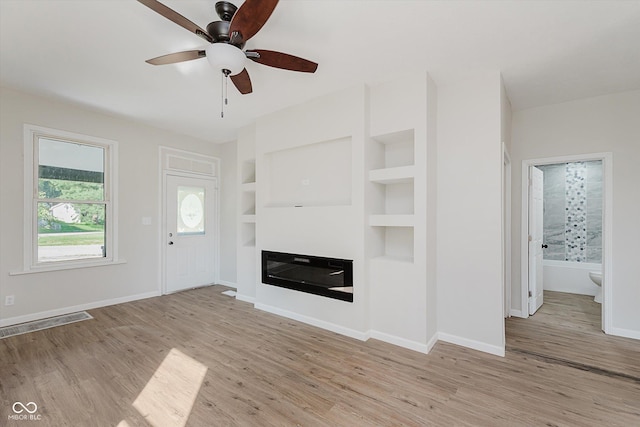 312 E Columbia St, Attica, IN 47918 - unfurnished living room featuring wood finished floors, ceiling fan, a glass covered fireplace, and built in shelves