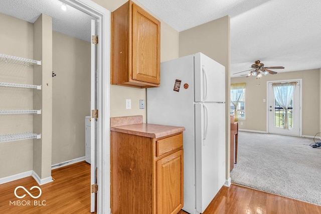 5971 Portman Pl, Plainfield, IN 46168 - kitchen with freestanding refrigerator, ceiling fan, light wood-style floors, light countertops, and a textured ceiling