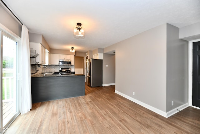 3675 Homestead Cir E, Plainfield, IN 46168 - kitchen with appliances with stainless steel finishes, dark countertops, wood finished floors, decorative backsplash, and a peninsula