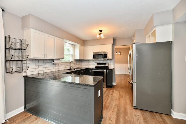 3675 Homestead Cir E, Plainfield, IN 46168 - kitchen with appliances with stainless steel finishes, a peninsula, backsplash, light wood-style flooring, and white cabinetry