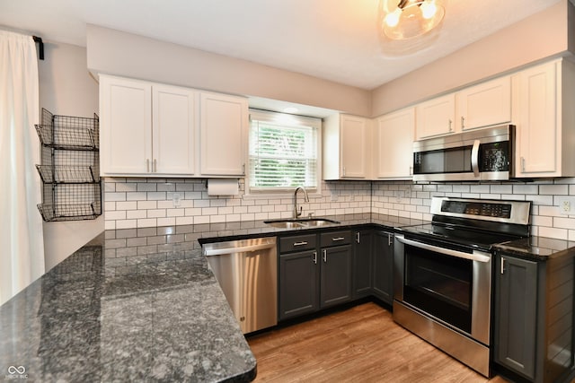 3675 Homestead Cir E, Plainfield, IN 46168 - kitchen with stainless steel appliances, light wood finished floors, white cabinets, and dark stone counters