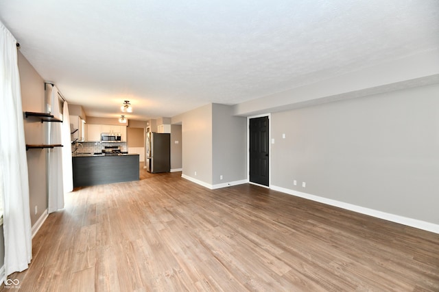 3675 Homestead Cir E, Plainfield, IN 46168 - unfurnished living room featuring baseboards and light wood-style floors