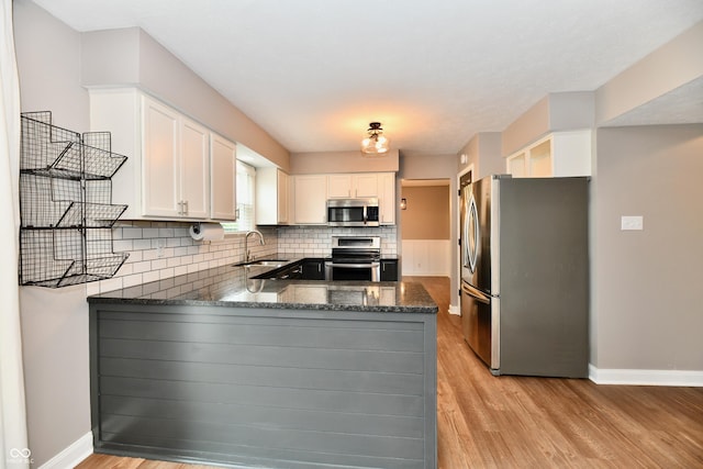 3675 Homestead Cir E, Plainfield, IN 46168 - kitchen featuring stainless steel appliances, a peninsula, decorative backsplash, light wood-style flooring, and white cabinetry