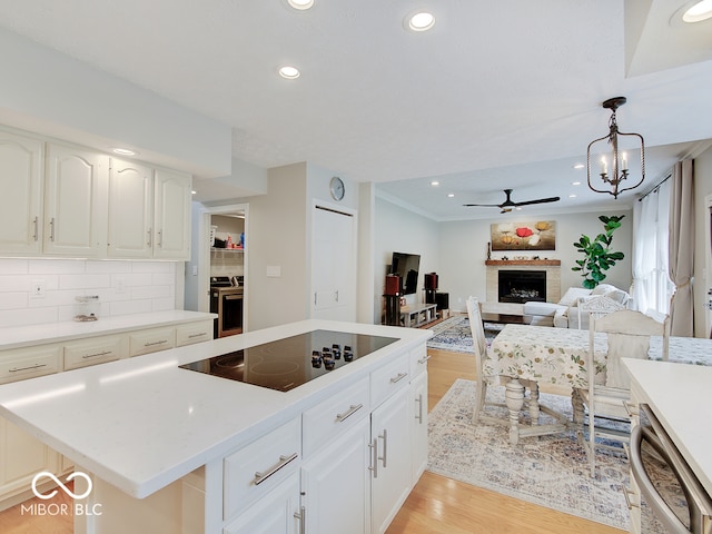 11668 Victoria Ct, Carmel, IN 46033 - kitchen featuring black electric cooktop, light wood-style floors, a fireplace, light countertops, and recessed lighting