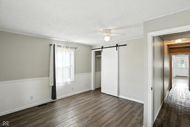363 N 19th Ave, Beech Grove, IN 46107 - unfurnished bedroom featuring dark wood-style floors, a barn door, a textured ceiling, a closet, and a ceiling fan