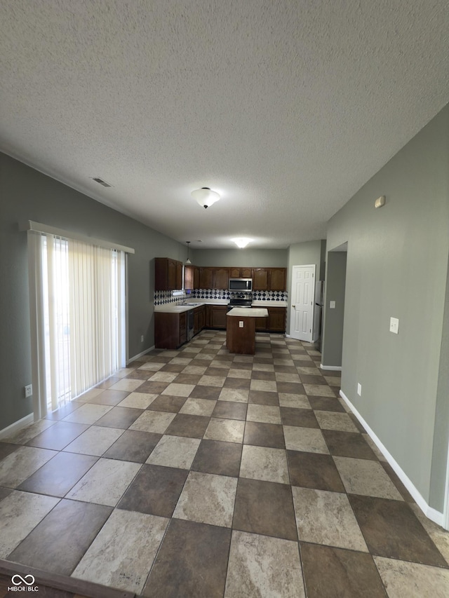 1881 Harvest Meadow Dr, Greenwood, IN 46143 - kitchen with light countertops, stainless steel microwave, open floor plan, a kitchen island, and a textured ceiling