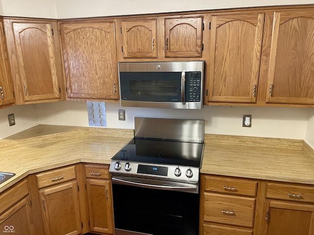 7410 Crickwood Pl, Indianapolis, IN 46268 - kitchen with appliances with stainless steel finishes, light countertops, and brown cabinets