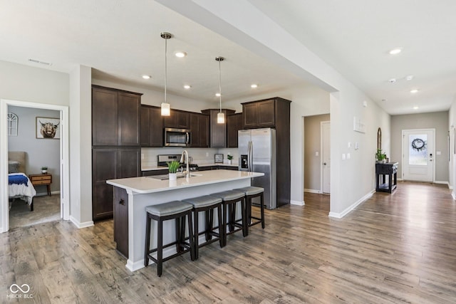 338 Limerick Ln, Pendleton, IN 46064 - kitchen featuring stainless steel appliances, dark brown cabinets, light countertops, a kitchen island with sink, and a kitchen breakfast bar
