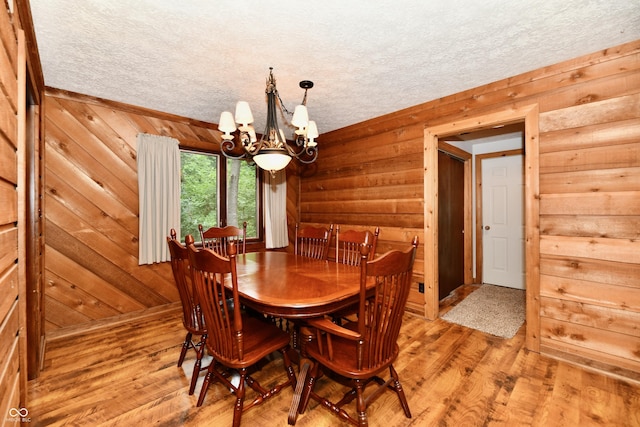 5202 Hill Valley Dr, Pittsboro, IN 46167 - dining room featuring a chandelier, light wood finished floors, wood walls, and a textured ceiling