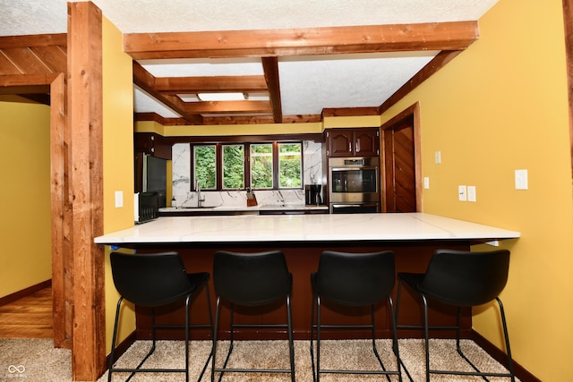 5202 Hill Valley Dr, Pittsboro, IN 46167 - kitchen with a peninsula, beam ceiling, double oven, a breakfast bar, and freestanding refrigerator