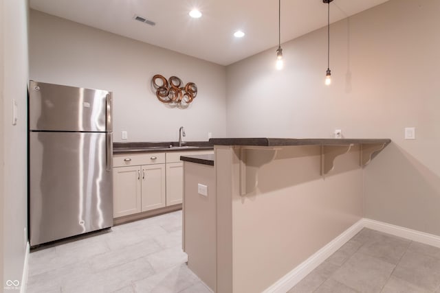 1434 Shootingstar Way, West Lafayette, IN 47906 - kitchen with freestanding refrigerator, dark countertops, hanging light fixtures, a kitchen breakfast bar, and a peninsula