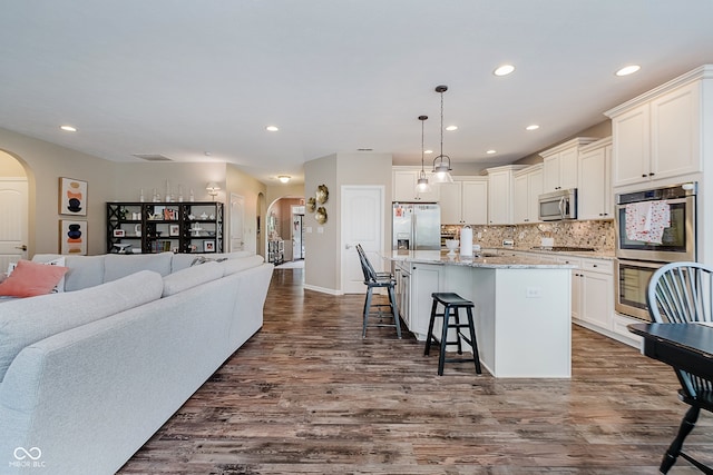 801 Oaklawn Dr, Westfield, IN 46074 - kitchen featuring stainless steel appliances, arched walkways, open floor plan, a kitchen island with sink, and a breakfast bar area