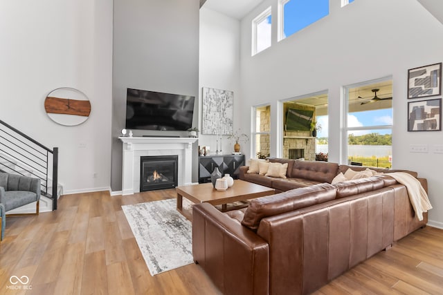 13644 Haven Cove Ln, Fishers, IN 46055 - living room with a tiled fireplace, stairway, a towering ceiling, light wood finished floors, and ceiling fan