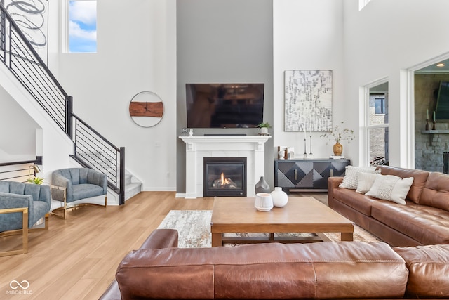 13644 Haven Cove Ln, Fishers, IN 46055 - living area with a glass covered fireplace, a high ceiling, stairway, wood finished floors, and plenty of natural light