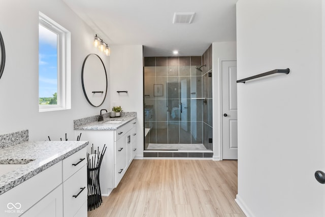 13644 Haven Cove Ln, Fishers, IN 46055 - bathroom featuring two vanities, a stall shower, and wood finished floors