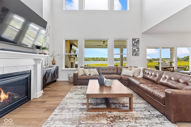 13644 Haven Cove Ln, Fishers, IN 46055 - living room with a tiled fireplace, wood finished floors, a high ceiling, and a water view