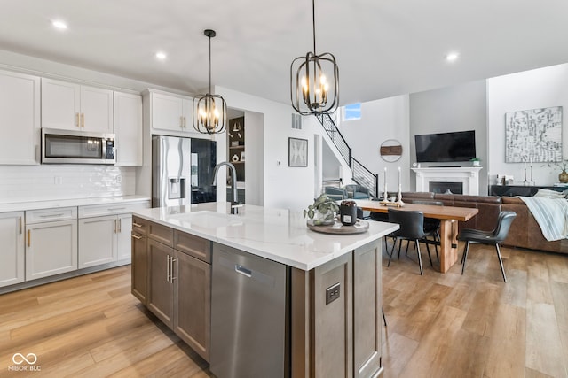 13644 Haven Cove Ln, Fishers, IN 46055 - kitchen with stainless steel appliances, open floor plan, light wood finished floors, a fireplace, and white cabinetry