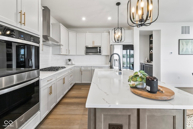 13644 Haven Cove Ln, Fishers, IN 46055 - kitchen with stainless steel appliances, wall chimney range hood, a chandelier, decorative backsplash, and an island with sink